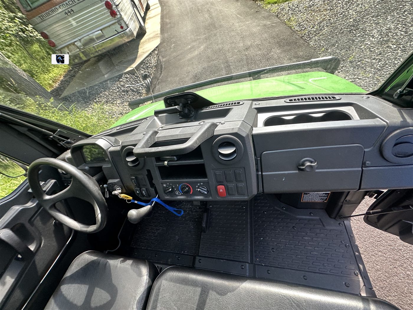 John Deere Gator interior before deep cleaning — dusty dash, floor mats, and controls