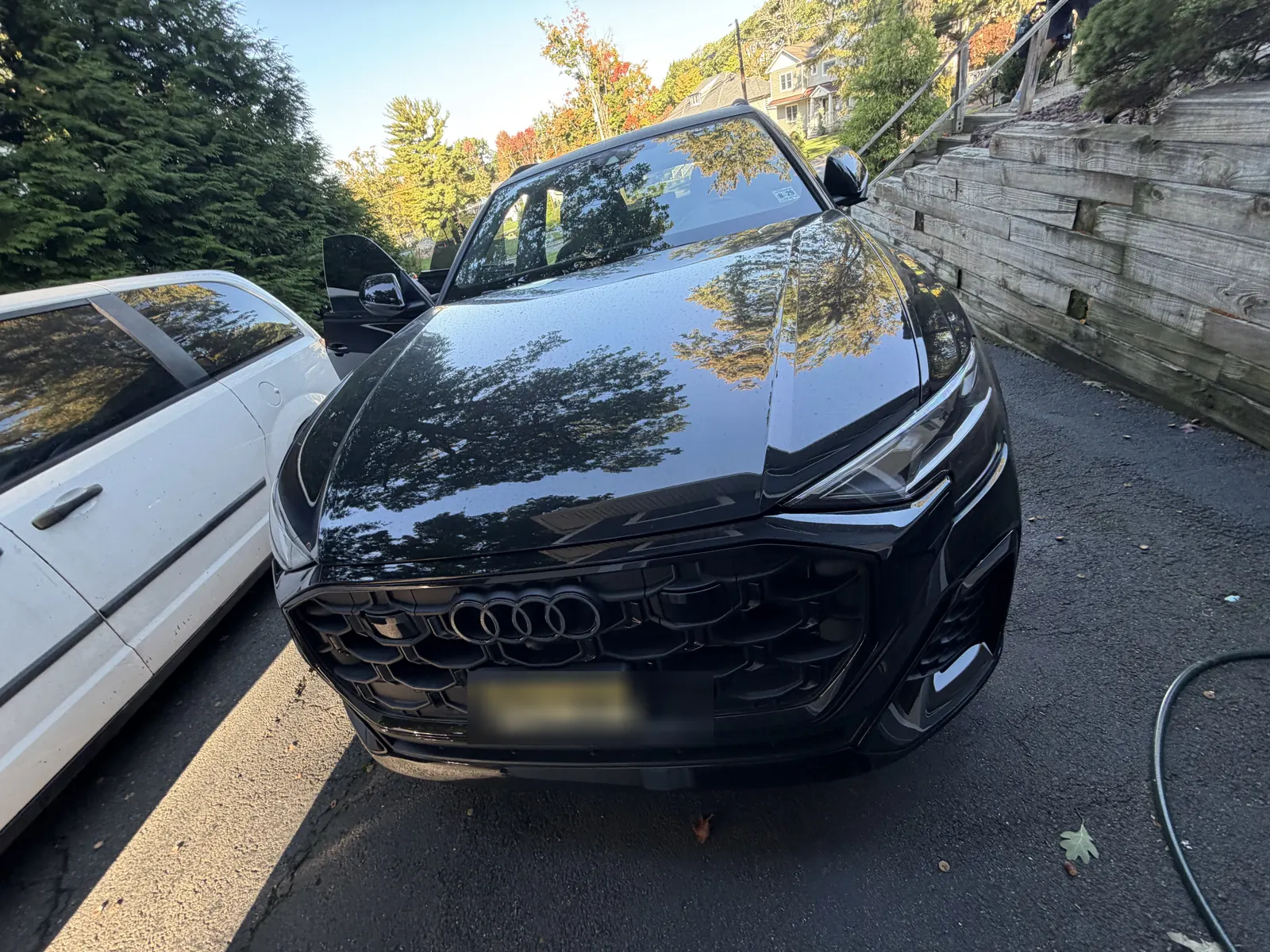 Black Audi Q8 front view in a driveway. The license plate is covered.