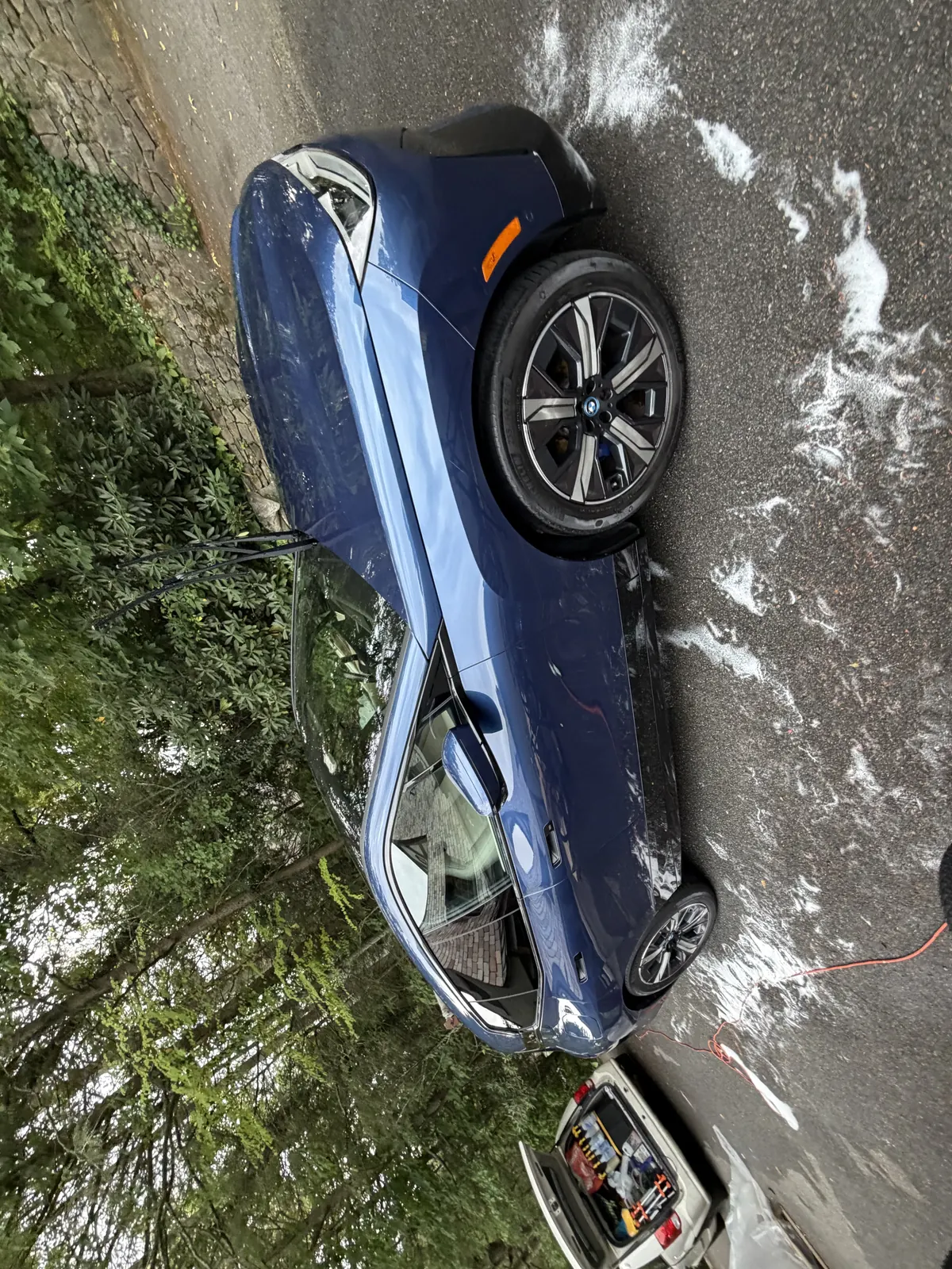 Blue BMW during an exterior wash, with soap on the paint