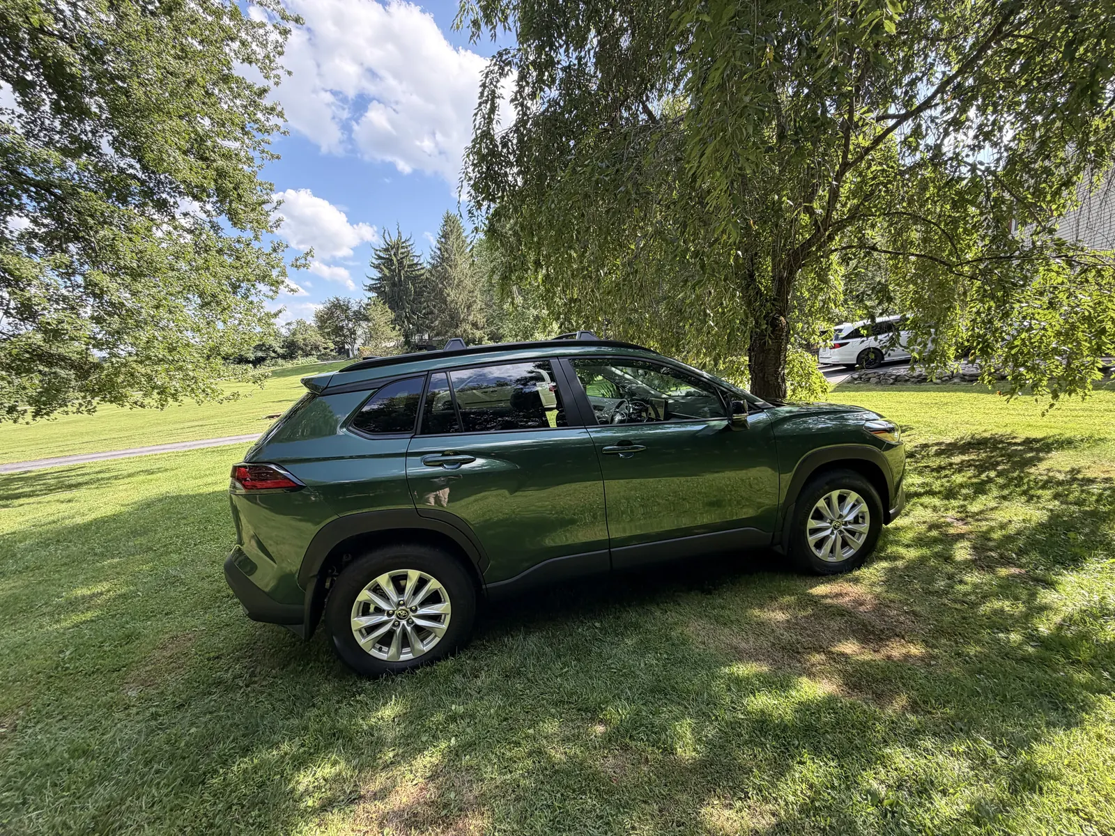 Dark green Toyota Corolla Cross side view on a lawn